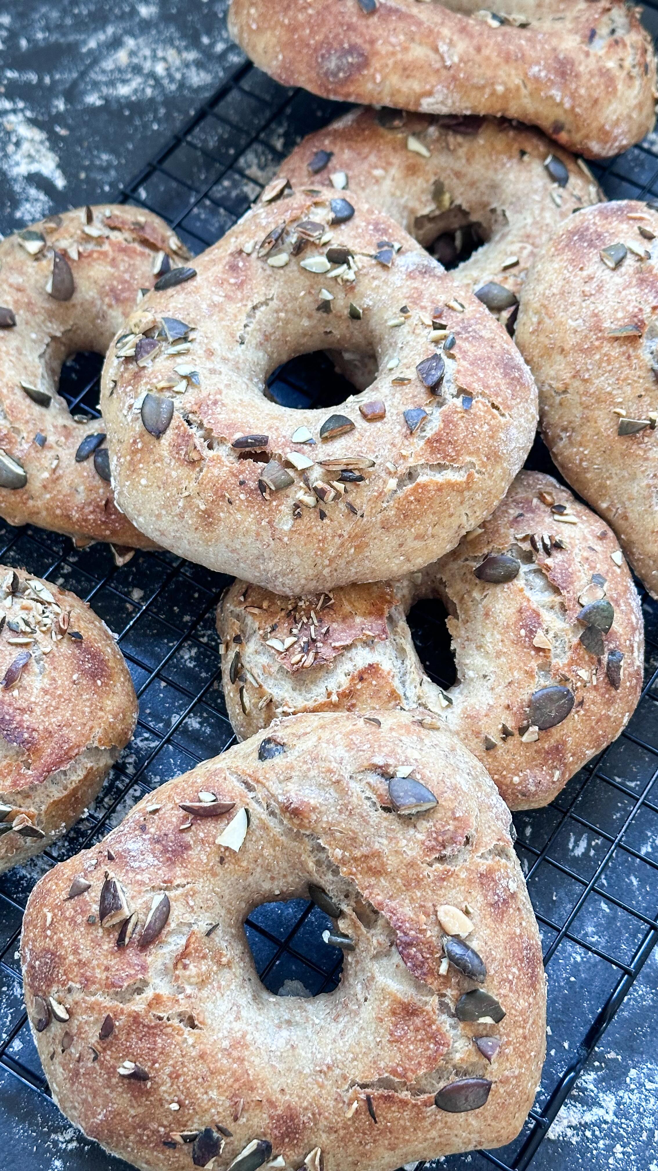 Kernige Kürbiskringel mit Sauerteig 🥯

360ml Wasser, 100g Roggensauerteig, 130g Weizenvollkornmehl, 320g Weizenmehl 550, 50g Roggenmehl 1150 —> kurz miteinander verkneten und für 1 Stunde stehen lassen. 
12g Salz hinzufügen und den Teig gut durchkneten. Dann 30g Kürbiskerne unterheben. 
Den Teig bei Zimmertemperatur für 3 Stunden ruhen lassen. Nach einer und nach 2 Stunden dehnen und falten. Dann über Nacht im Kühlschrank ruhen lassen.
Am nächsten Morgen den Teig in acht Teile teilen. Jeweils in die Mitte von einem Teigstück mit einem Kochlöffel, ein Loch stechen und dann mit den Händen zu Kringeln formen.
Mit Wasser einstreichen und mit gehackten Kürbiskern bestreuen. 
Bei 220° im Ofen für circa 20-25 Minuten backen. 

#brotbacken #sauerteig #sauerteigbrot #gesundesfrühstück #zuckerfreibacken
